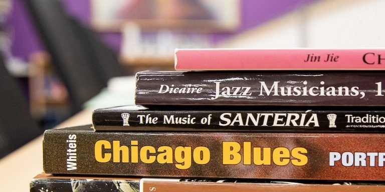 a selection of books stacked on a table covering blues, Santeria, jazz, and Chinese music.