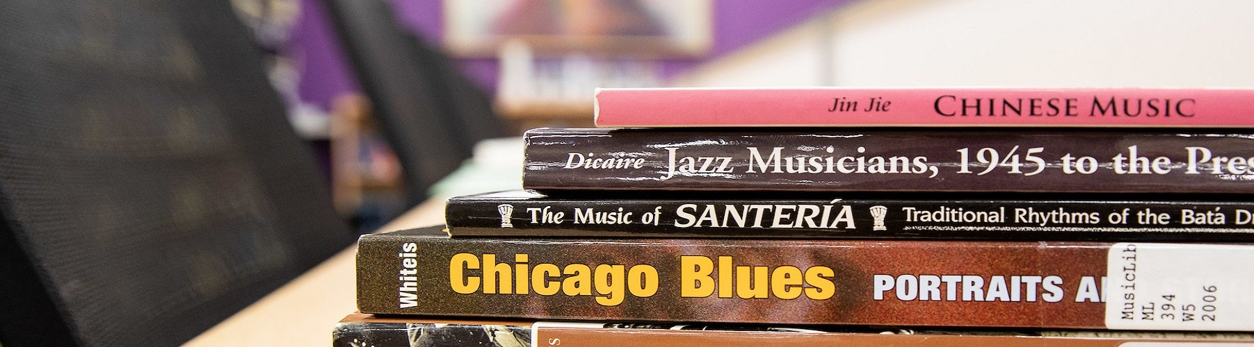 a selection of books stacked on a table covering blues, Santeria, jazz, and Chinese music.