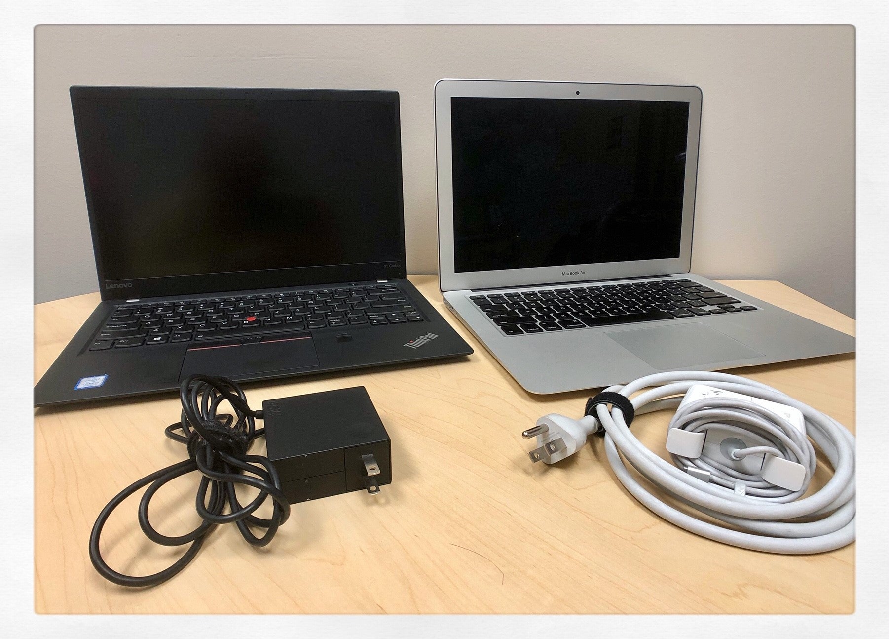 PC laptop with charger sitting beside a Mac laptop with charger