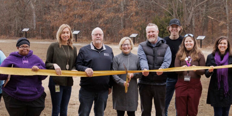 Group of people performing ribbon-cutting with large scissors at Wildwood Park.