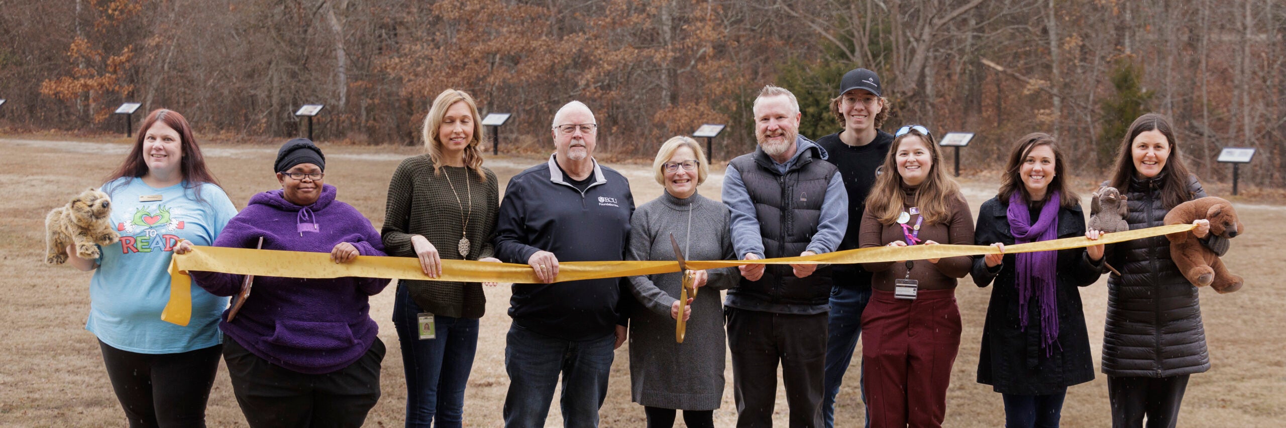 Group of people performing ribbon-cutting with large scissors at Wildwood Park.