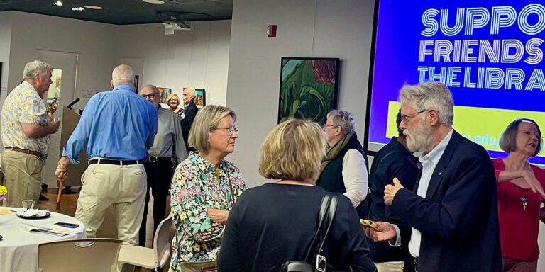 People gathered and talking in a library art gallery.