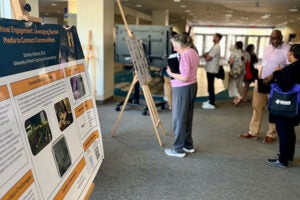 People look at posters displayed on the first floor of a library.