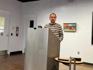 A man standing at a podium in a stripped sweater